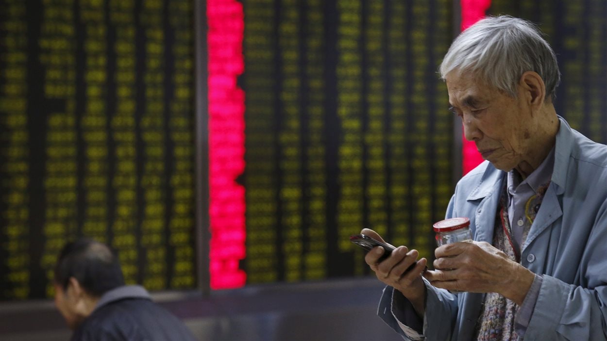 Un investisseur chinois consulte son téléphone devant une maison de courtage de Pékin.