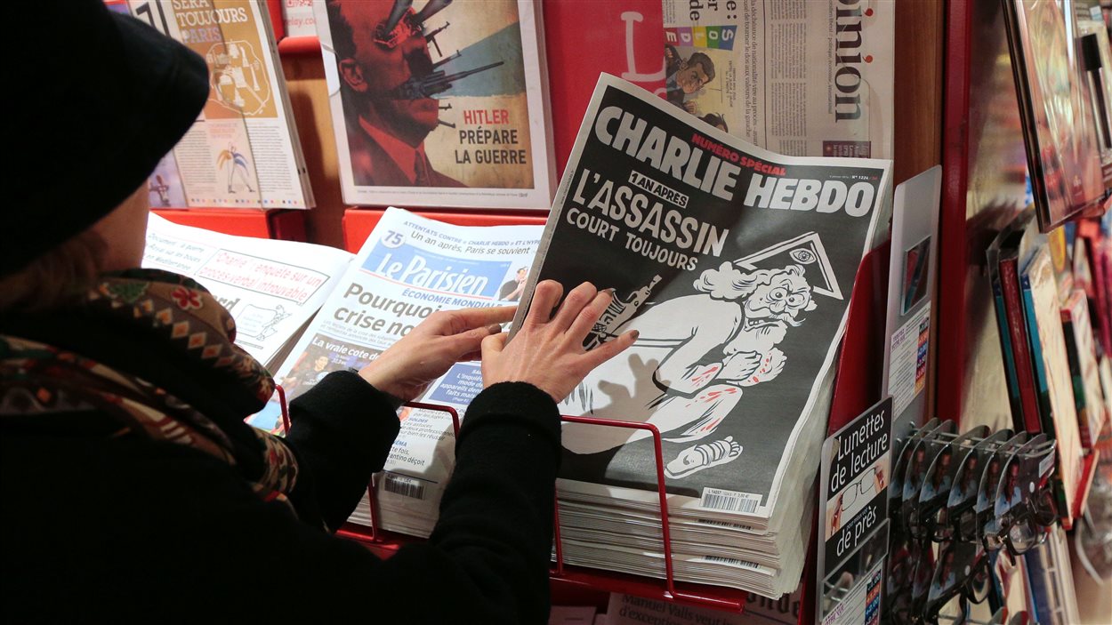 Une femme prend une édition commémorative du journal satirique Charlie Hebdo à un kiosque à journaux, à Paris, le 6 janvier 2015.