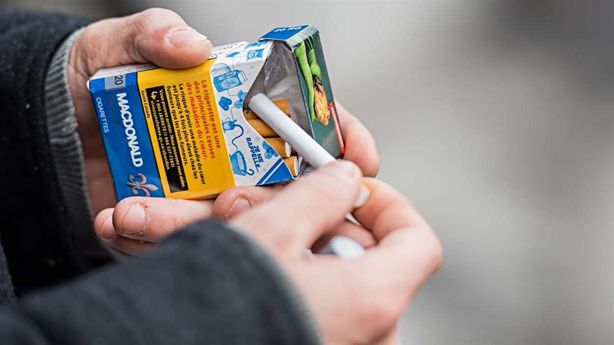 Un homme sort une cigarette d’un paquet.