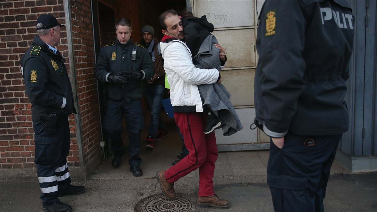 La police danoise escorte un migrant syrien et son enfant, après l'avoir intercepté dans un train, le 6 janvier. Le Danemark venait de rétablir des mesures de contrôle pour les migrants en provenance d'Allemagne.