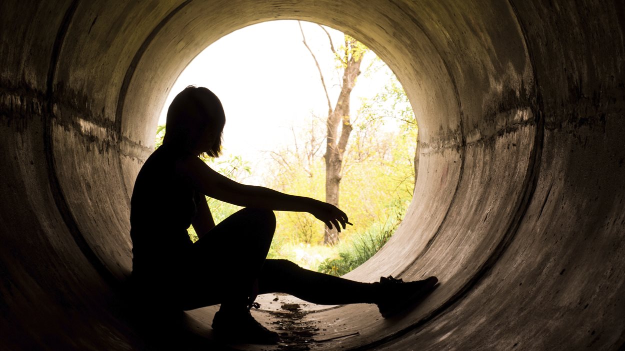 Une femme, dans un tunnel, fume une cigarette.