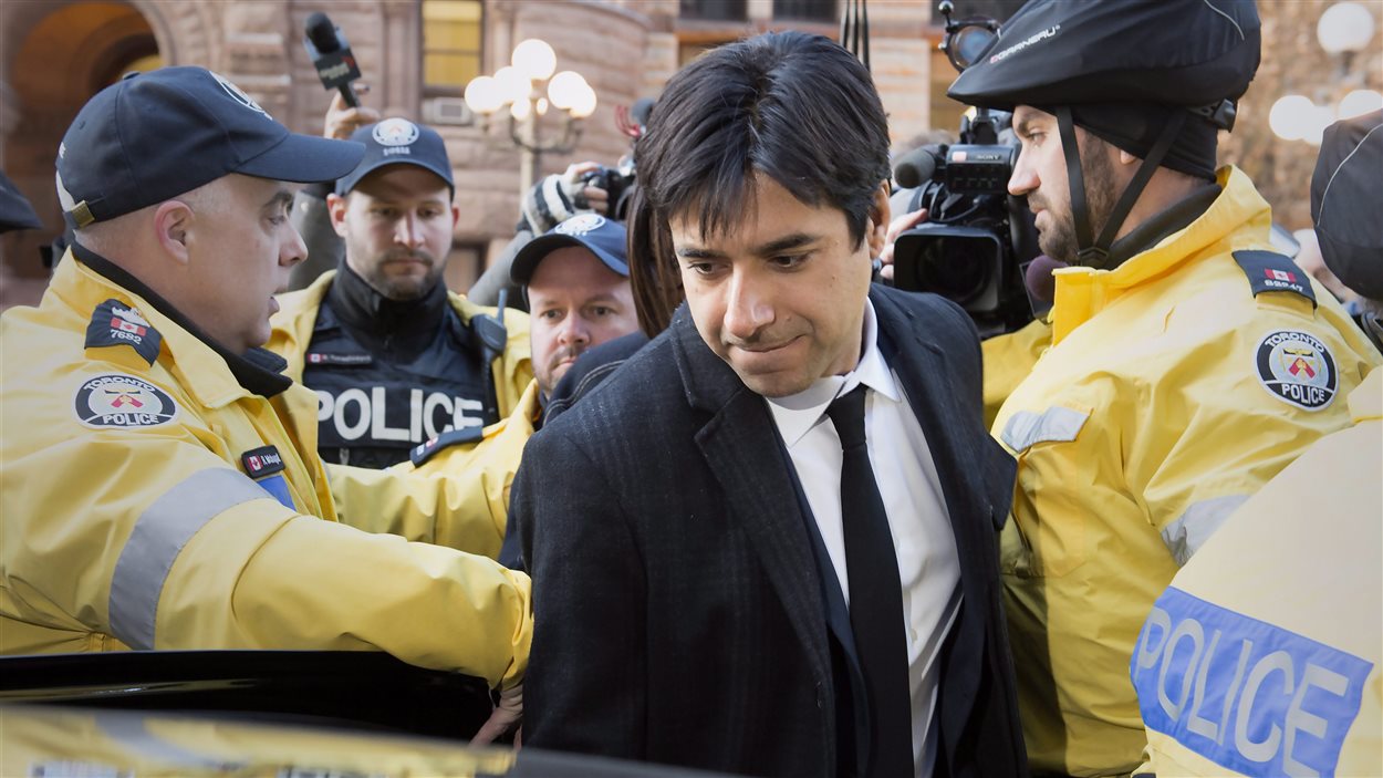 Jian Ghomeshi quitte le tribunal escorté par des policiers.