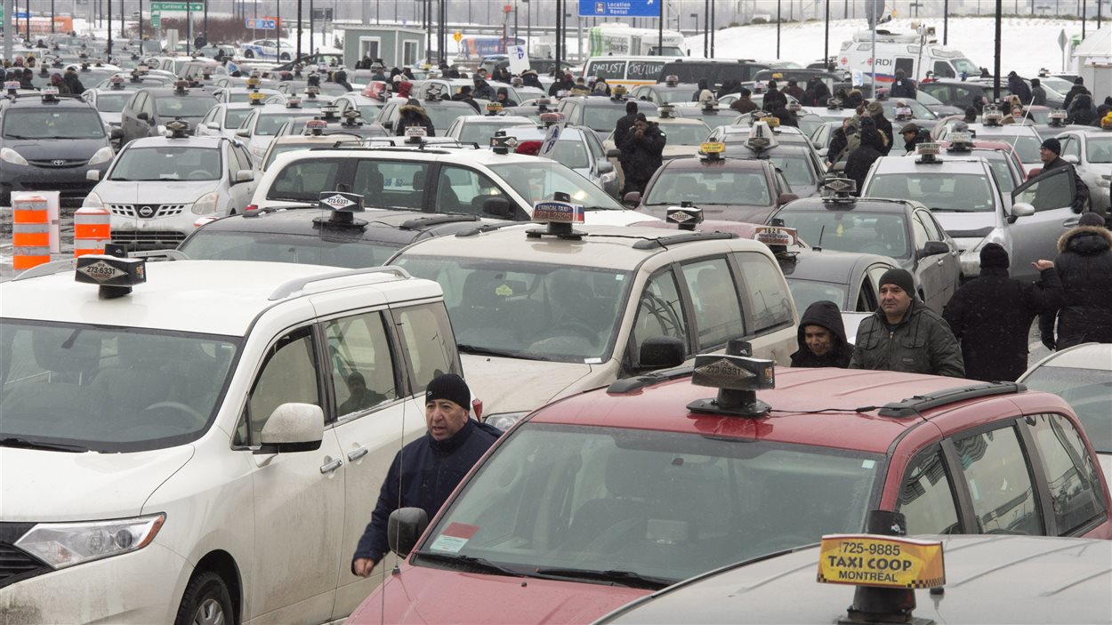 Plusieurs centaines de chauffeurs de taxi bloquent la circulation à l'aéroport Trudeau de Montréal. le 10 février, pour protester contre Uber.