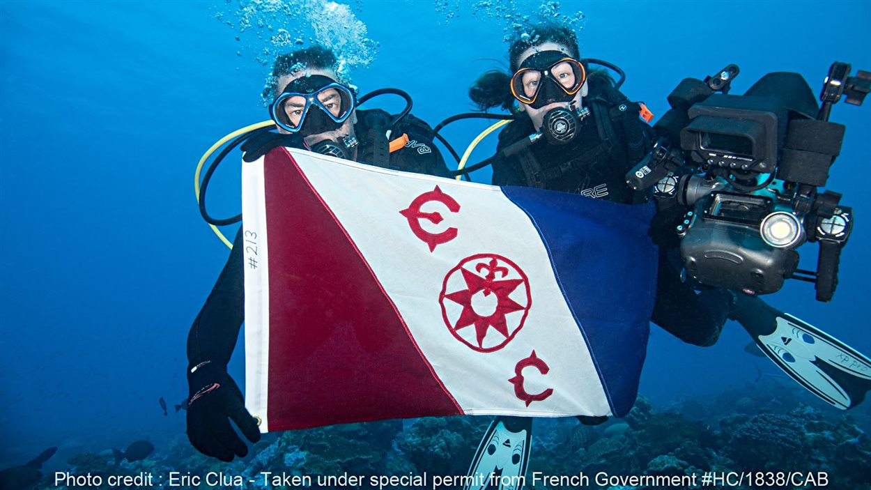 Michel Labrecque et Julie Ouimet présente le drapeau du Explorer Club de New York lors de leur mission au coeur du Pacifique.