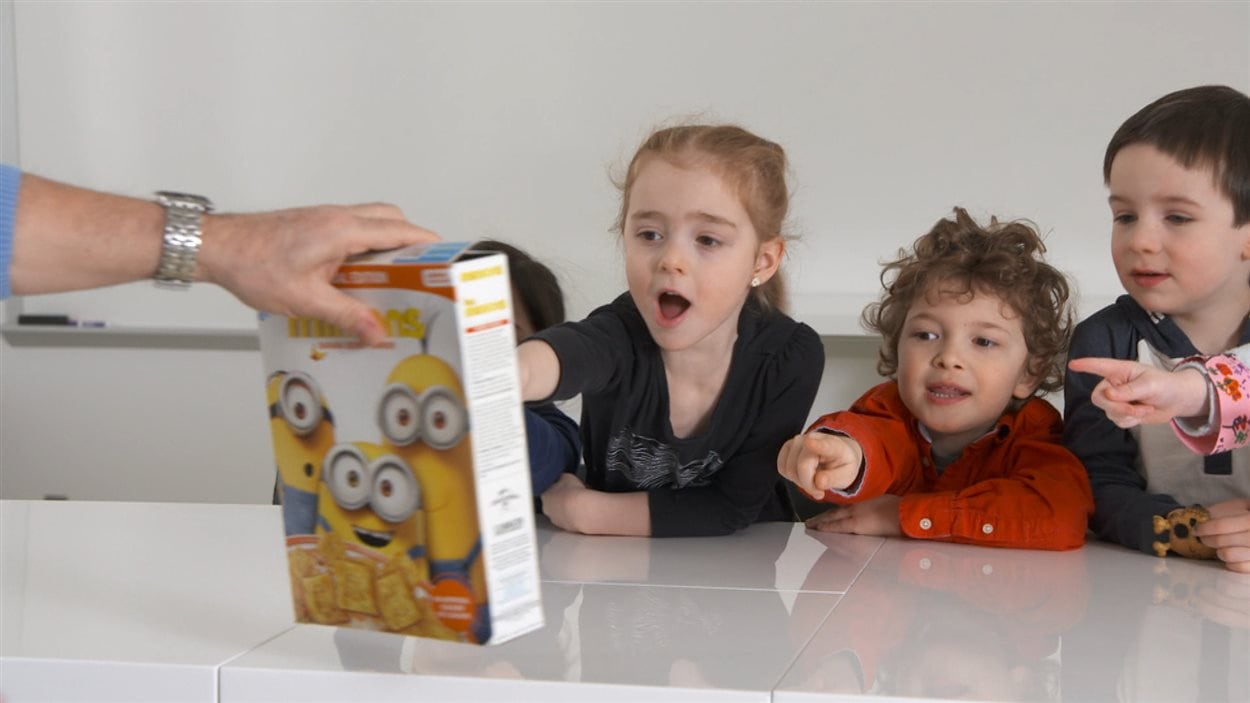 Des enfants réagissent devant une boîte de céréales aux couleurs des Mignons.