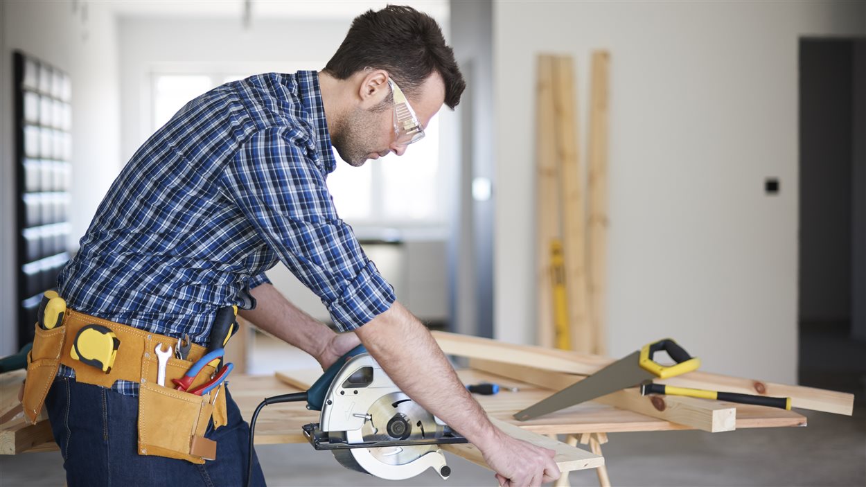 Un homme coupe une planche de bois