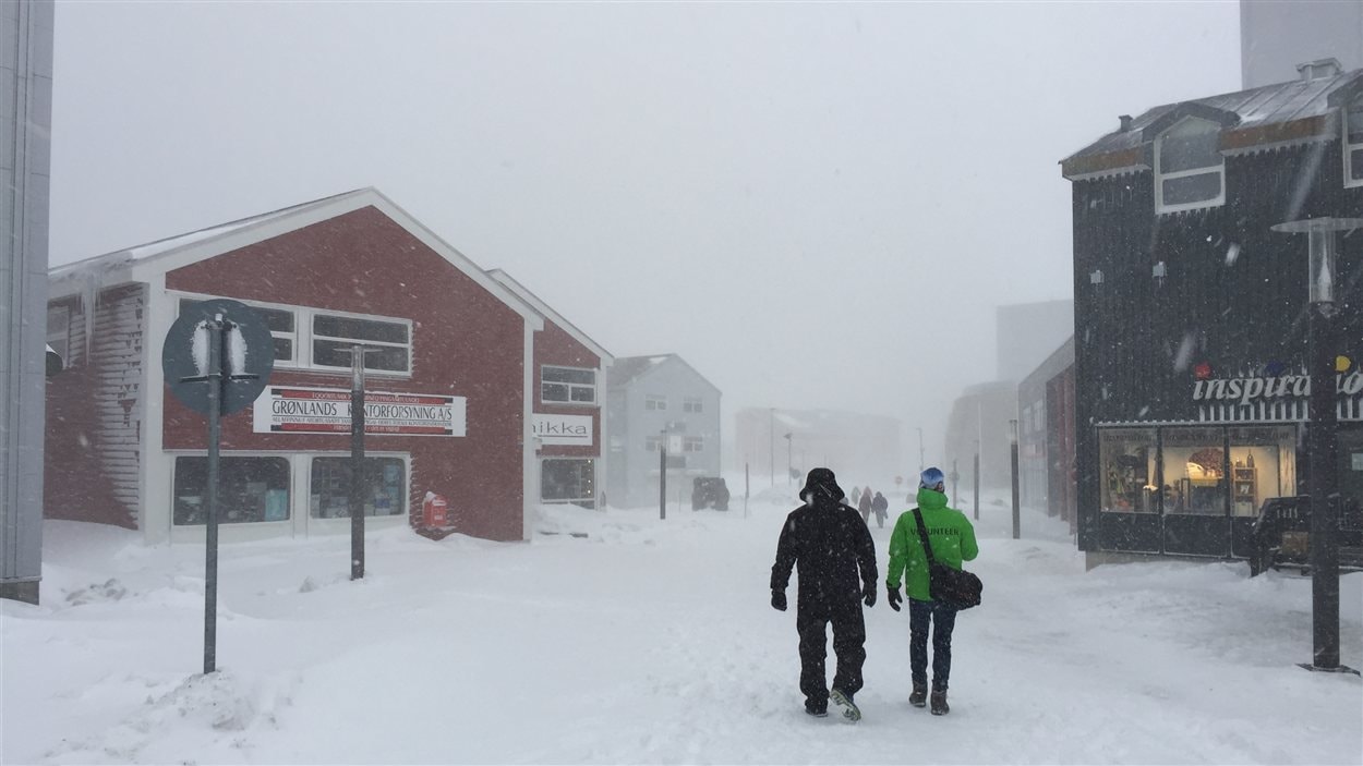 deux hommes marchent une rue piétonnière à Nuuk dans la tempête