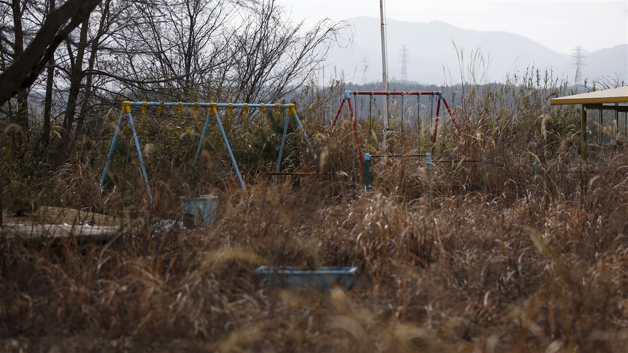 Balançoires d'une cour de garderie couvertes d'herbes dans la zone d'exclusion à Okuma, près de Fukushima, le 13 février 2016.