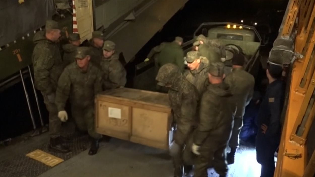 Cette photo fournie par le ministère russe de la Défense montrerait des soldats transportant du matériel militaire à bord d'un avion cargo sur la base militaire russe de Hmeymim, en Syrie.