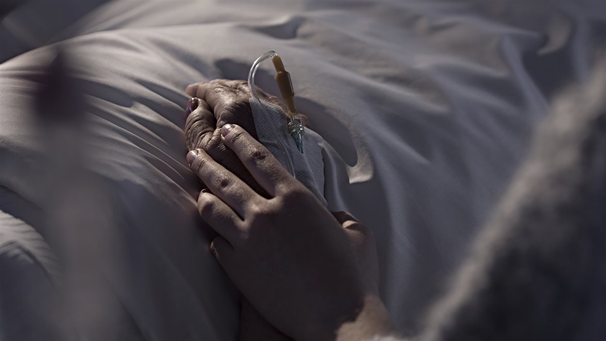 Une personne tient la main d'une ainée hospitalisée.