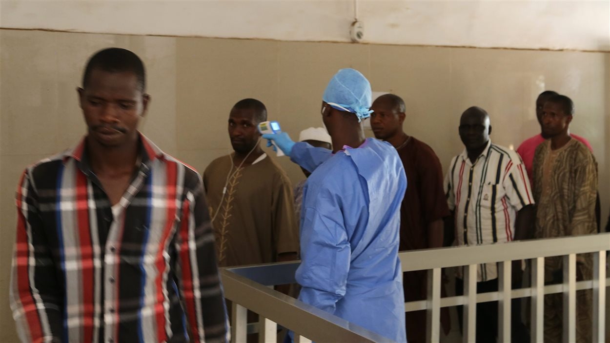 Un membre du personnel d'un hôpital de Conakry prend la température de personnes qui pourraient être infectées par le virus Ebola