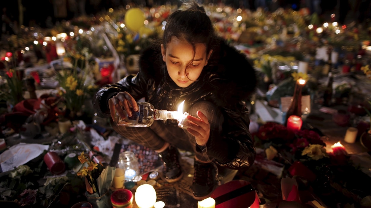 Une jeune fille allume un lampion à la Place de la bourse de Bruxelles en hommage aux victimes.