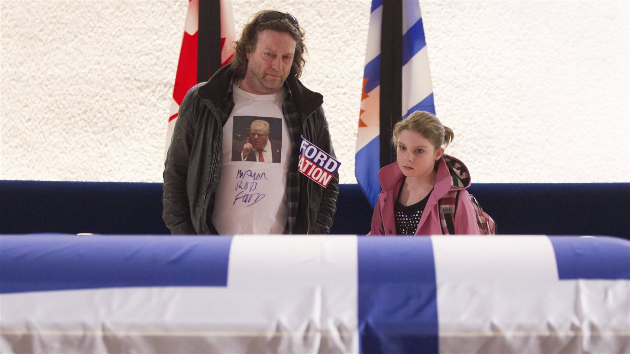 Un père et sa fille se recueillent près du cercueil de Rob Ford à l'hôtel de ville de Toronto.