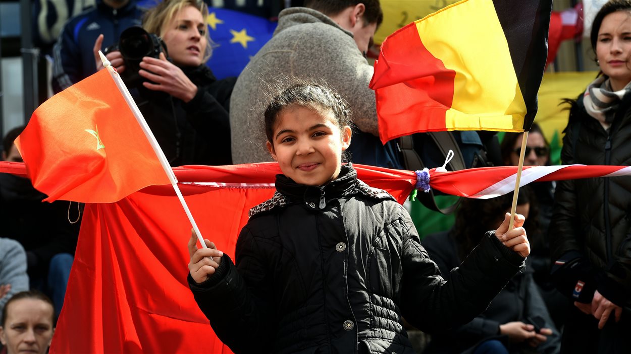 Une fillette tient des drapeaux belge et marocain lors d’un rassemblement en mémoire des victimes des attentats du 22 mars 2016, à Bruxelles, le 27 mars 2016.