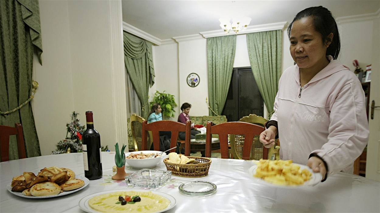 Une travailleuse domestique originaire des Philippines sert le souper à l'appartement de ses employeurs, en janvier 2010