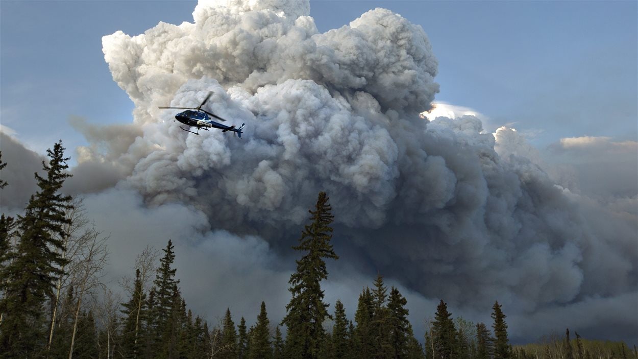 Un hélicoptère survole le feu de forêt dans la région de Fort McMurray.