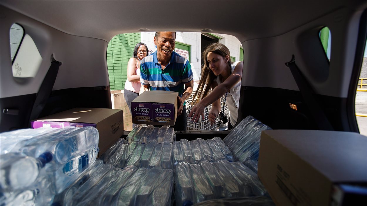 Des travailleurs sociaux remplissent de  denrées un véhicule de la banque alimentaire d'Edmonton pour aider les évacués de Fort McMurray.