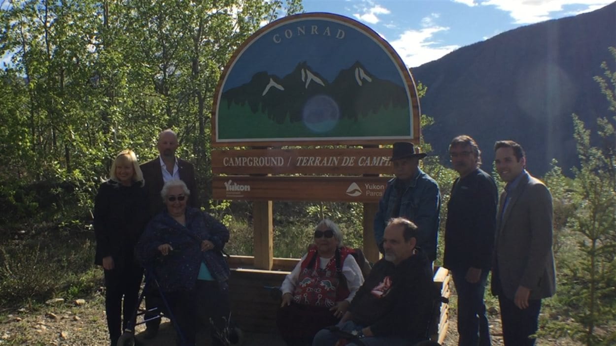 représentants du gouvernement du Yukon et de la Première Nation Carcross-Tagish devant l'affiche du camping
