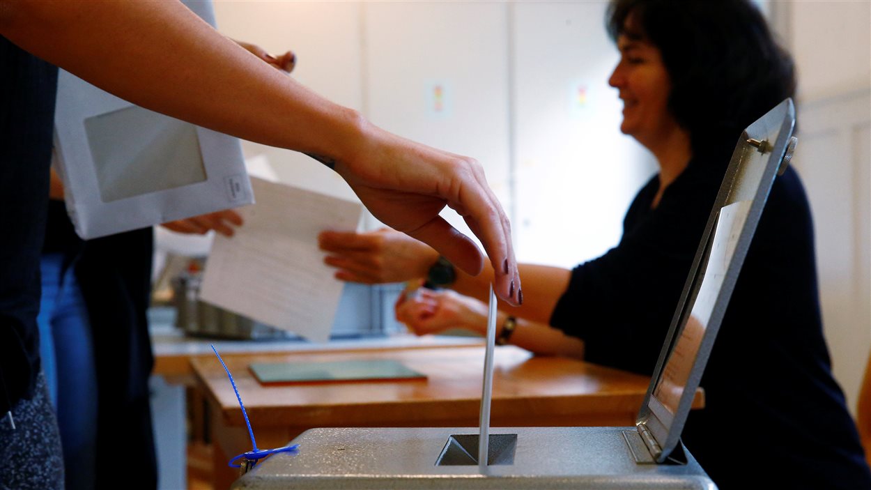Des électeurs déposent leurs bulletins de vote dans une école de Bern, en Suisse, durant une consultation sur l'idée d'un revenu de base inconditionnel, le 5 juin 2016.
