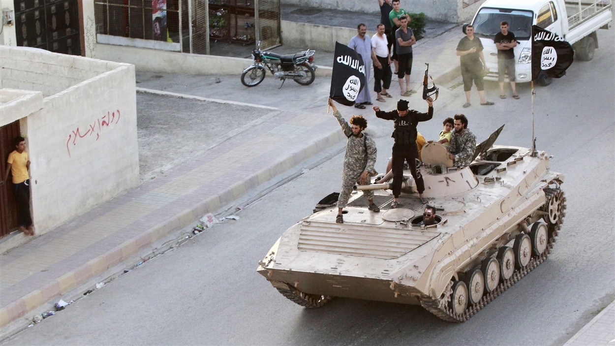 Des djihadistes brandissent le drapeau du groupe armé État islamique. 