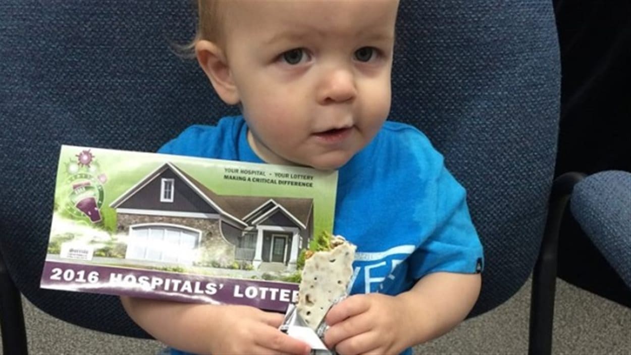 un bébé tient dans ses mains un ticket de loterie 