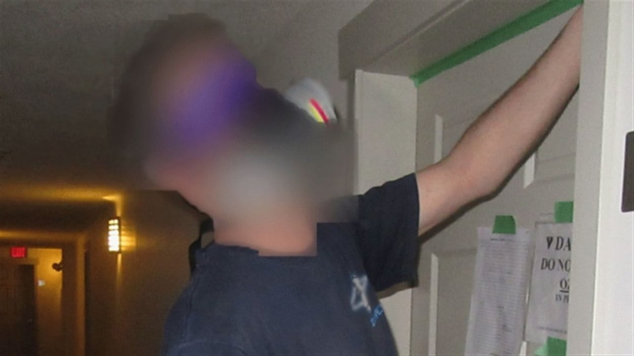Un nettoyeur de Fort McMurray portant un masque après avoir installé un générateur d'ozone dans une pièce. 