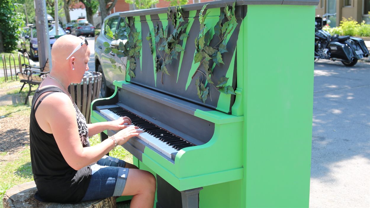 Une femme tente quelques notes sur le nouveau piano urbain installé à Limoilou.
