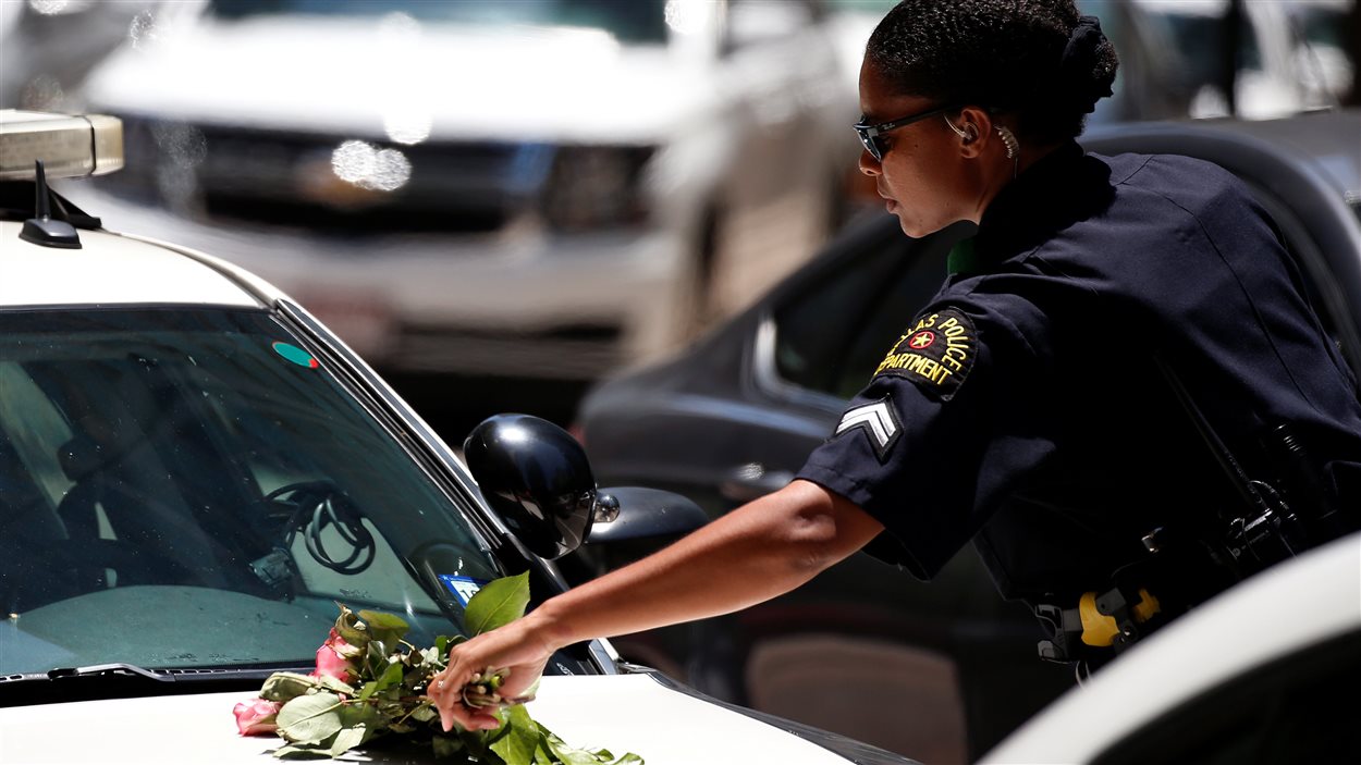Une policière de Dallas ramasse un bouquet de fleurs sur sa voiture après une veillée de prières dans un parc.