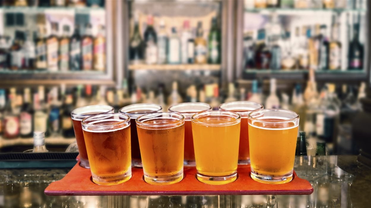Des bières artisanales sur un comptoir devant des réfrigérateurs pleins de bouteilles.