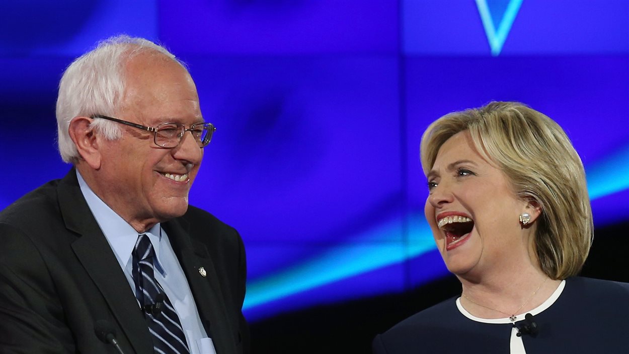 Bernie Sanders et Hillary Clinton, souriant à grandes dents, lors d'un débat télévisé à CNN en octobre 2015