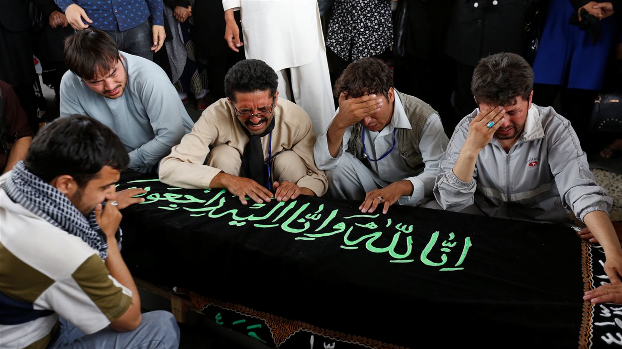 Des hommes pleurent au-dessus du cercueil d'une victime d'attentat à Kaboul le 24 juillet 2016.
