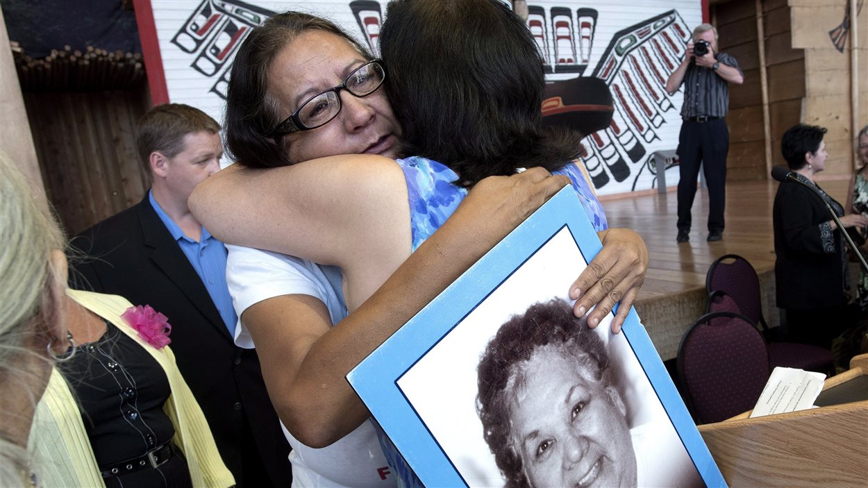 Bridget Tolley pleure après l'annonce sur l'Enquête nationale sur les femmes autochtones. Elle tient une photo de sa mère tuée en 2001.