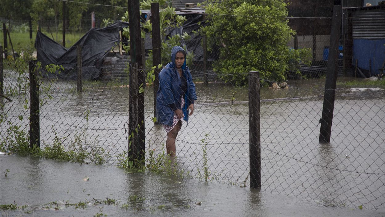Une femme se promène dans des eaux de crues devant chez elle à Dolores, dans l'État guatémaltèque frontalier au Belize, le 4 août 2016.