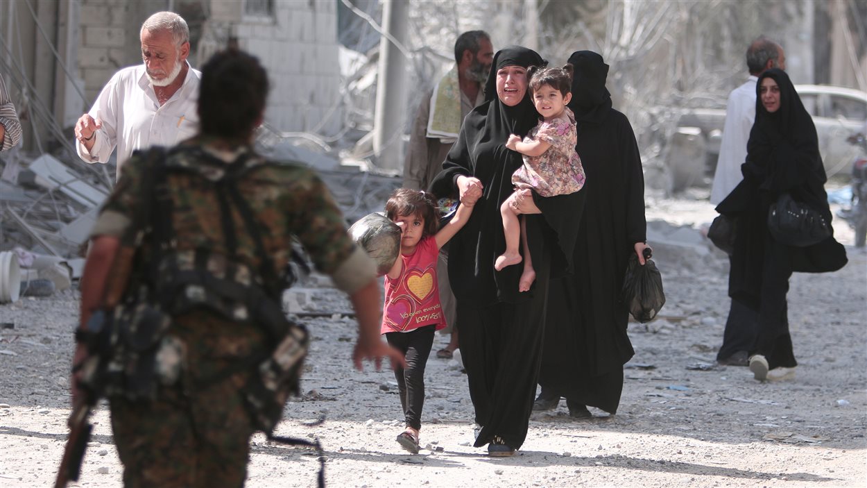 Un soldat rebelle se précipite pour aider des civils évacués d'un quartier de Manbij.