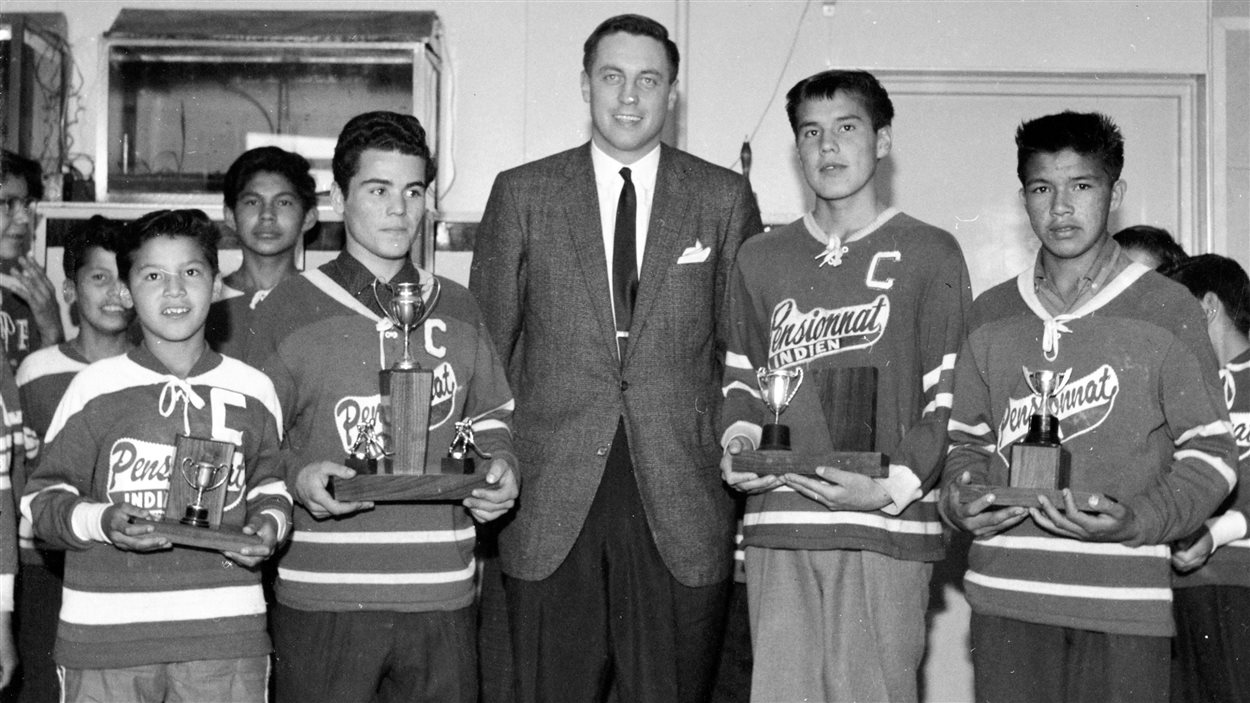 Jean Béliveau entouré de jeunes Autochtones membres de l'équipe de hockey du pensionnat