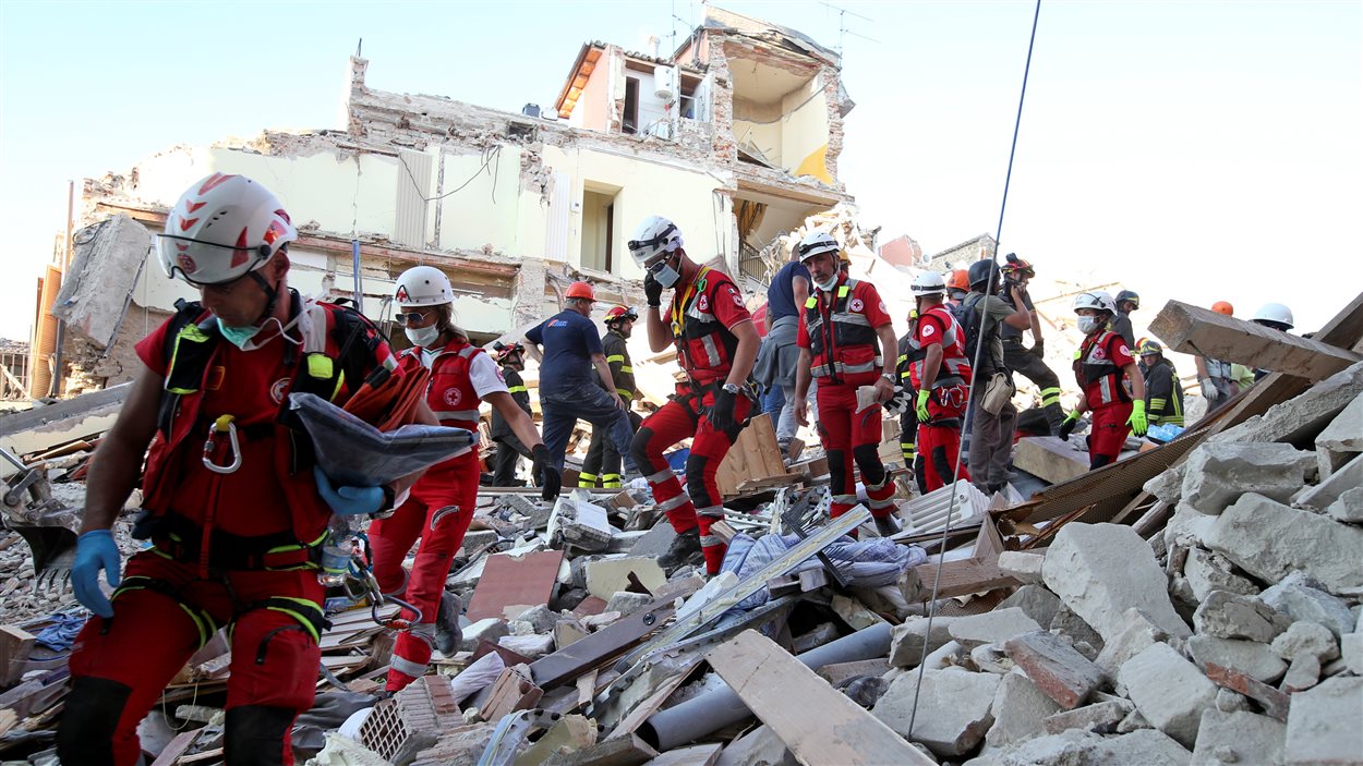 Des secouristes marchent à travers les décombres à Amatrice, au centre de l'Italie. 
