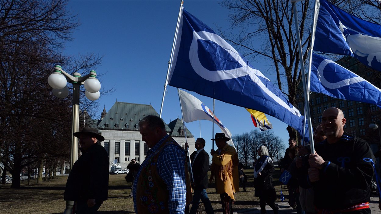 Des Métis défilent en tenant leur drapeau devant l'édifice abritant la Cour suprême du Canada, à Ottawa.