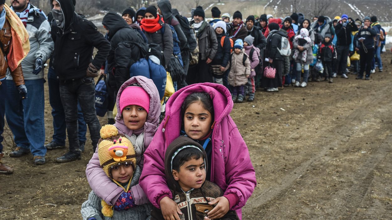 Des enfants attendent avec d’autres réfugiés à un poste de contrôle à la frontière entre la Macédoine et la Serbie fin janvier 2016.