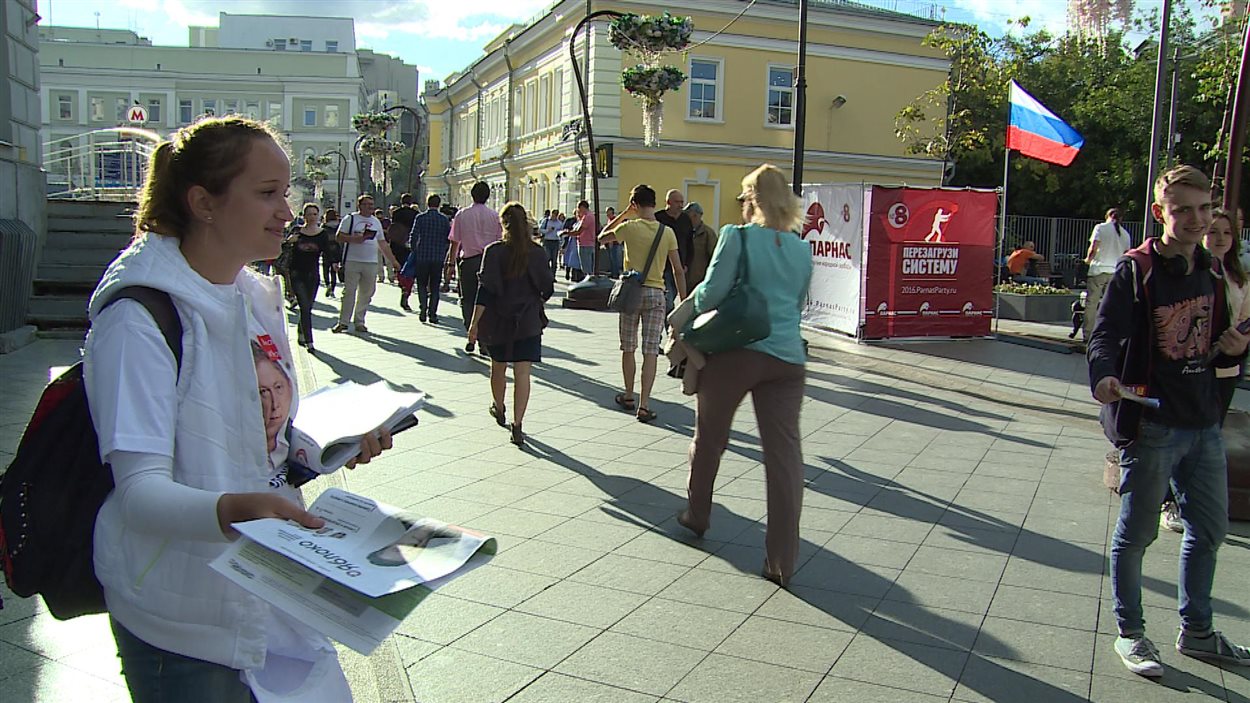 Des jeunes tentent de distribuer des journaux d'un parti d'opposition à des gens dans une rue de Moscou, mais peu de passants sont intéressés.