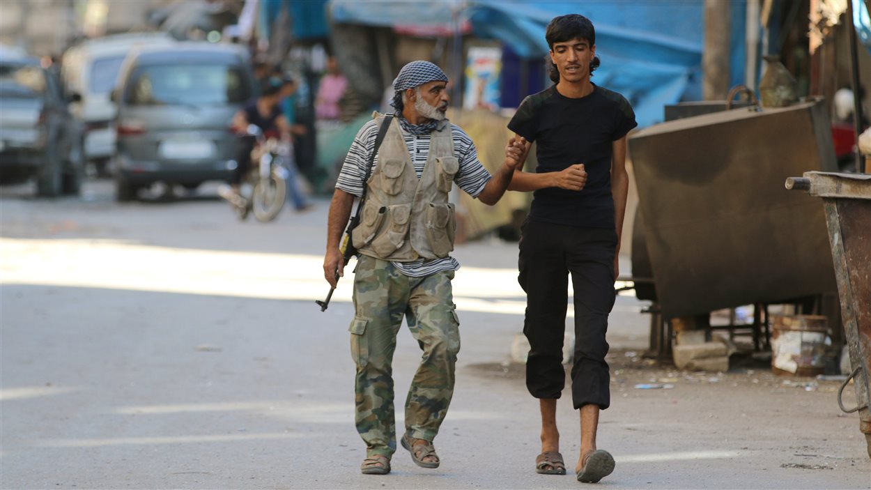 Des combattants rebelles marchent à l'intérieur d'un marché dans un quartier d'Alep, en Syrie.