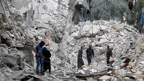 Dans le quartier rebelle de Tariq al-Bab, à Alep, des gens inspectent les dommages survenus en raison des frappes aériennes du régime syrien.