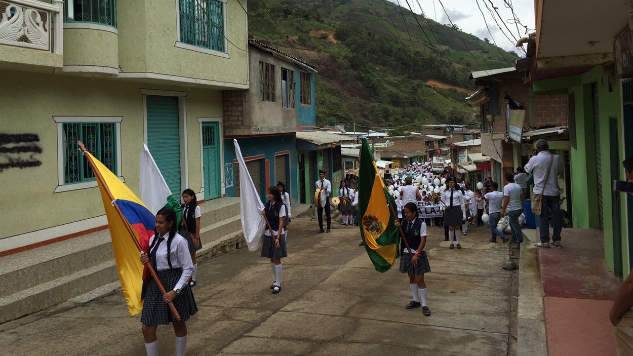 Des écoliers marchent dans la rue en portant des drapeaux