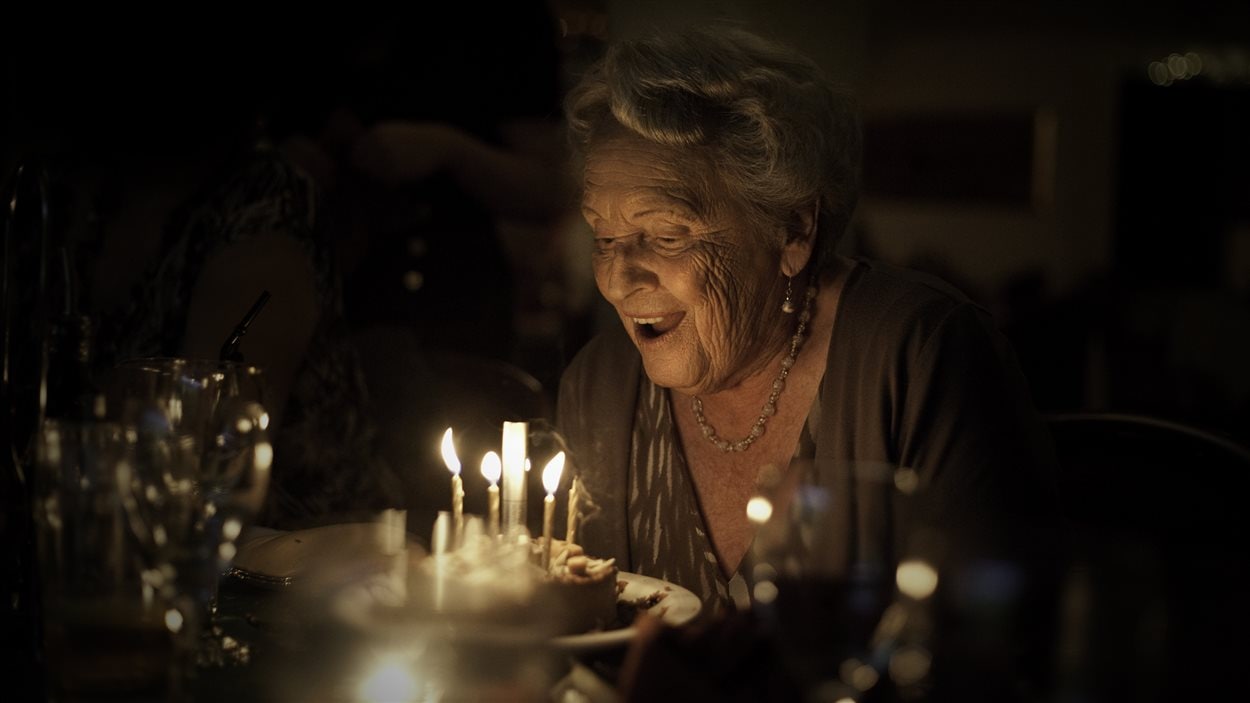 Une dame âgée souffle des bougies