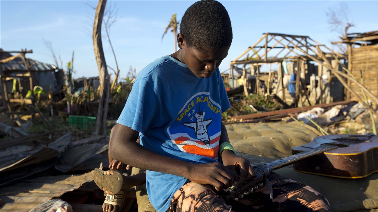 Un jeune garçon tente de réparer sa guitare à Hanse D’Hainault, en Haïti, le 11 octobre 2016, dans la dévastation causée par l’ouragan Matthew