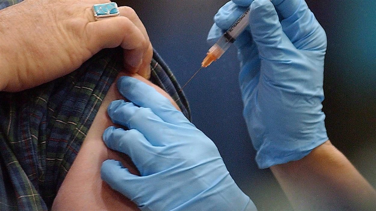 des mains avec des gants de médecin injectent une seringue pour vacciner dans le bras de quelqu'un.