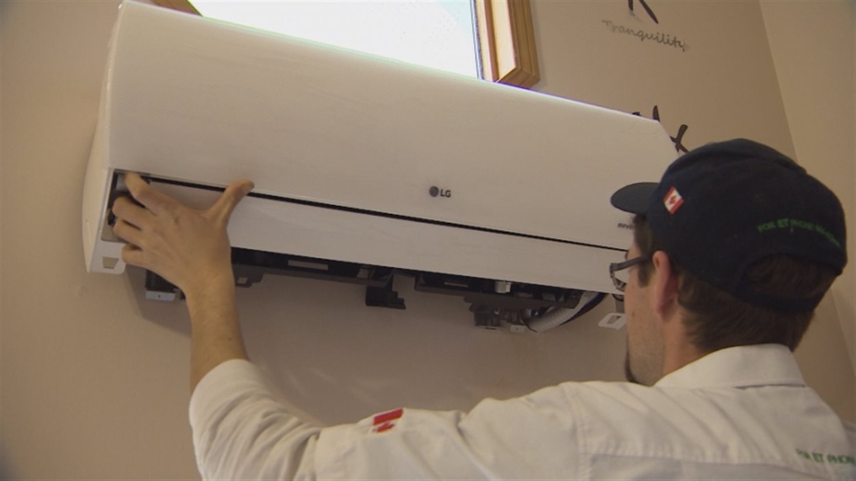 Un homme installe une thermopompe dans une maison