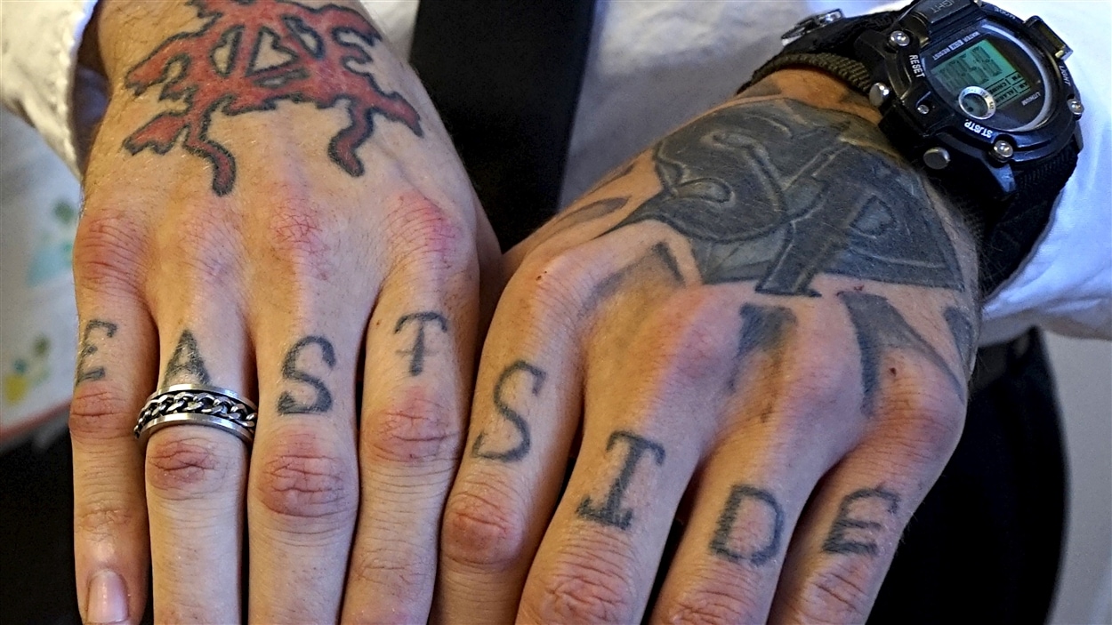 Un homme montre ses tatouages d'appatenance à des gangs de rue.
