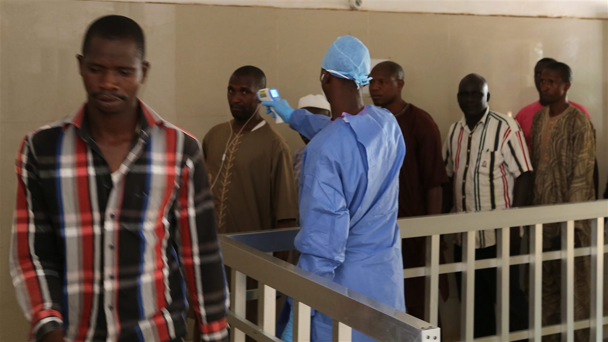Un travailleur de la santé prend la température de personnes en Guinée, le 18 mars 2016, pour s’assurer qu’ils ne soient pas infectés par le virus Ebola