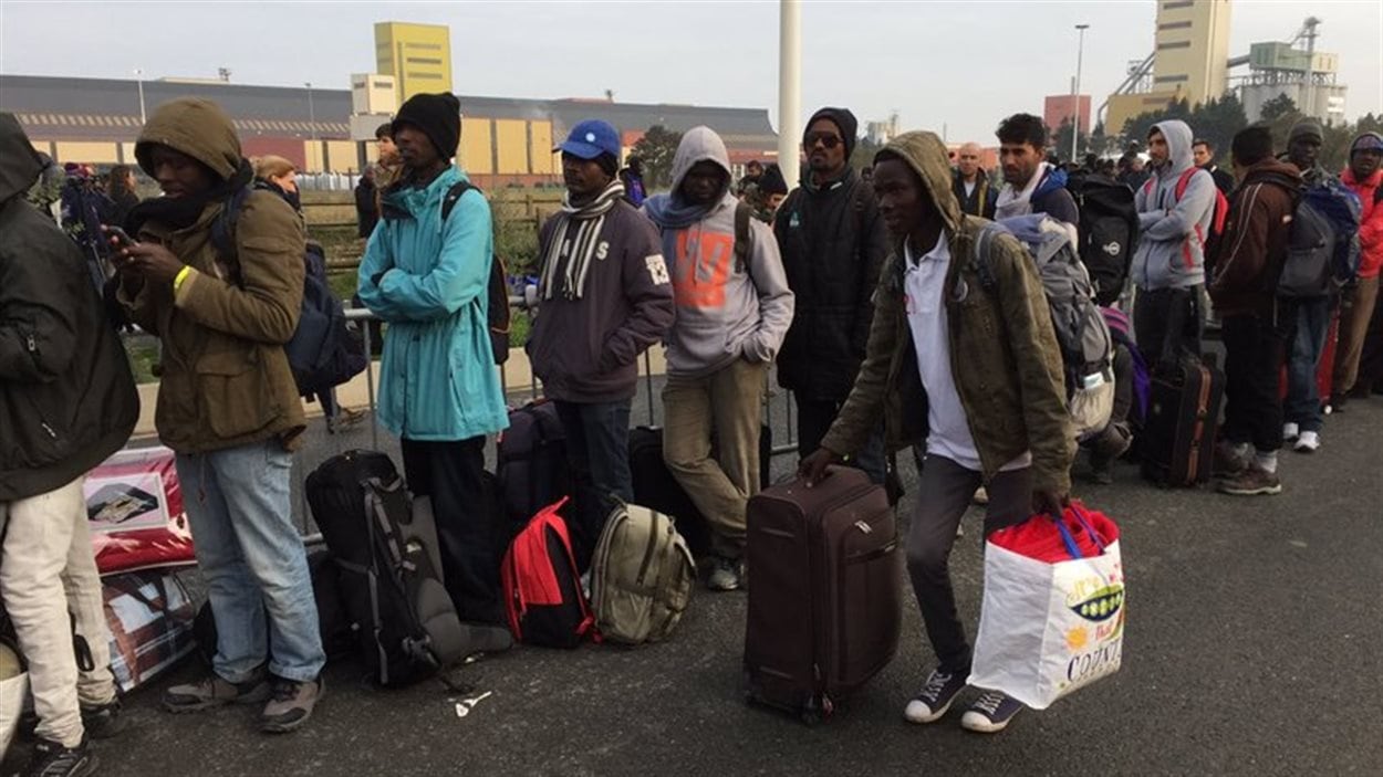 Des migrants font la file pour monter dans les autobus.