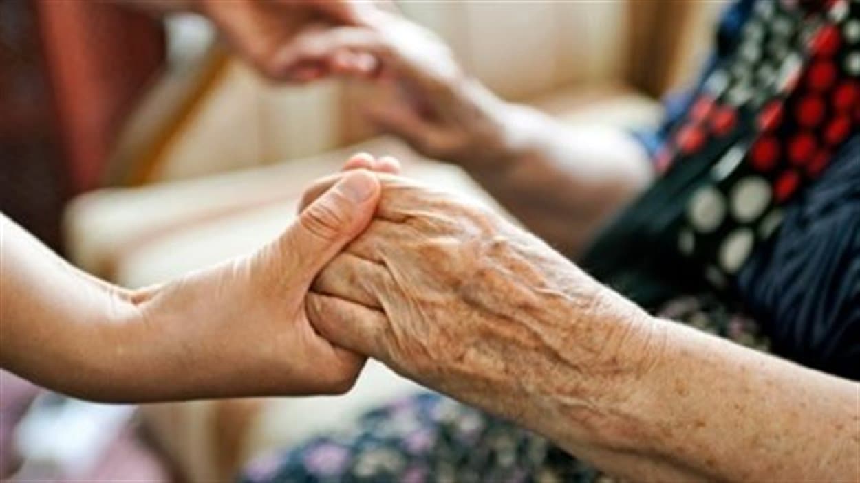 Un femme prend les mains d'une personne âgée